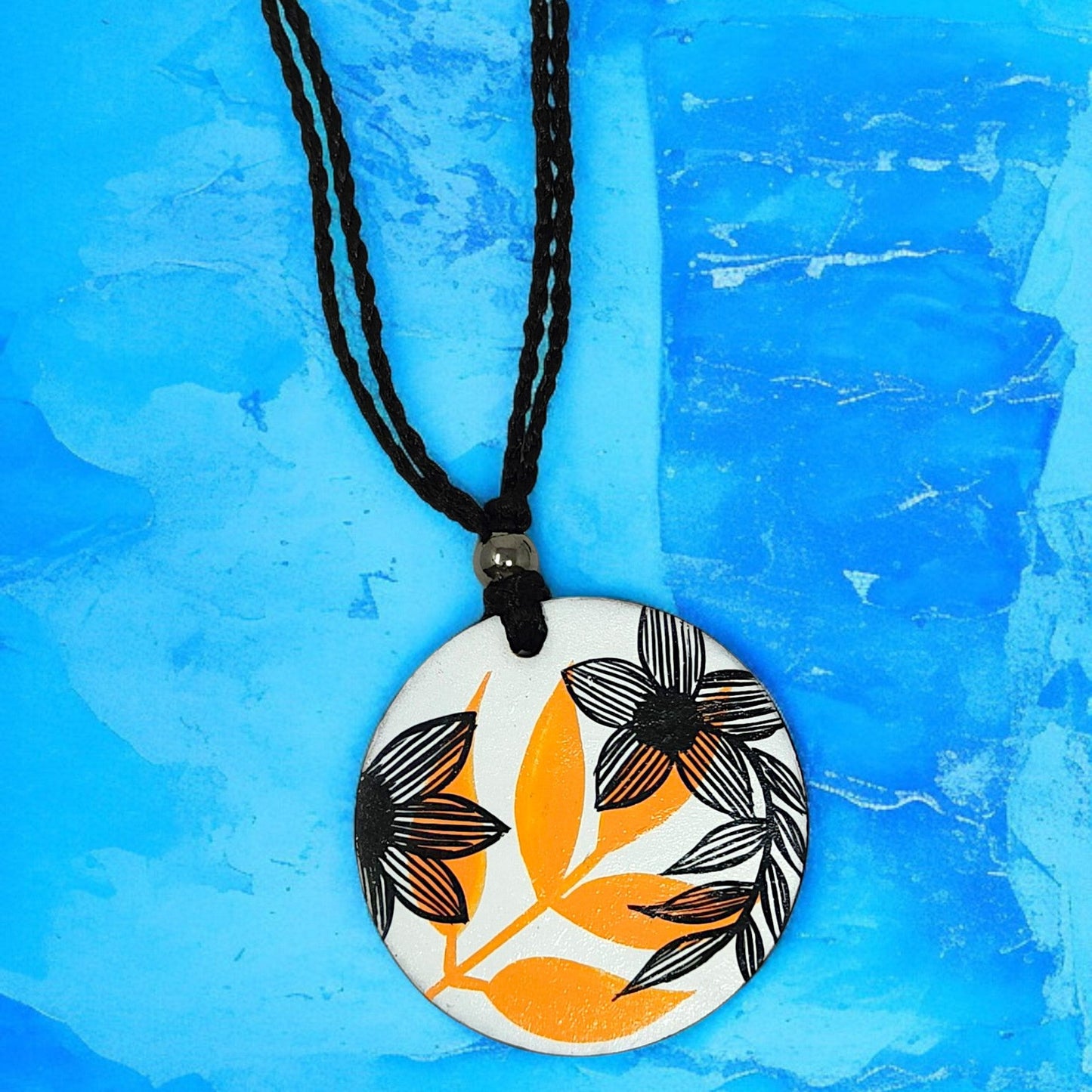Artisan Floral Pendant Necklace with black and orange floral design on round white base and black braided cord