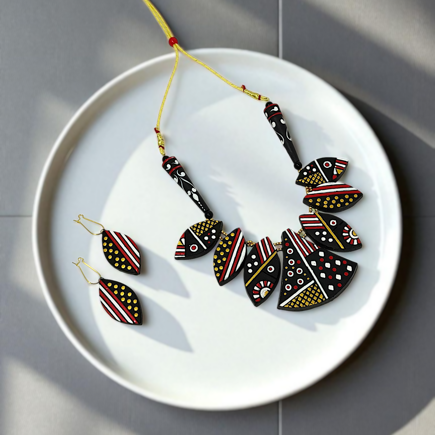 Black Trible jewelry Necklace Set with geometric patterns and matching earrings on white plate