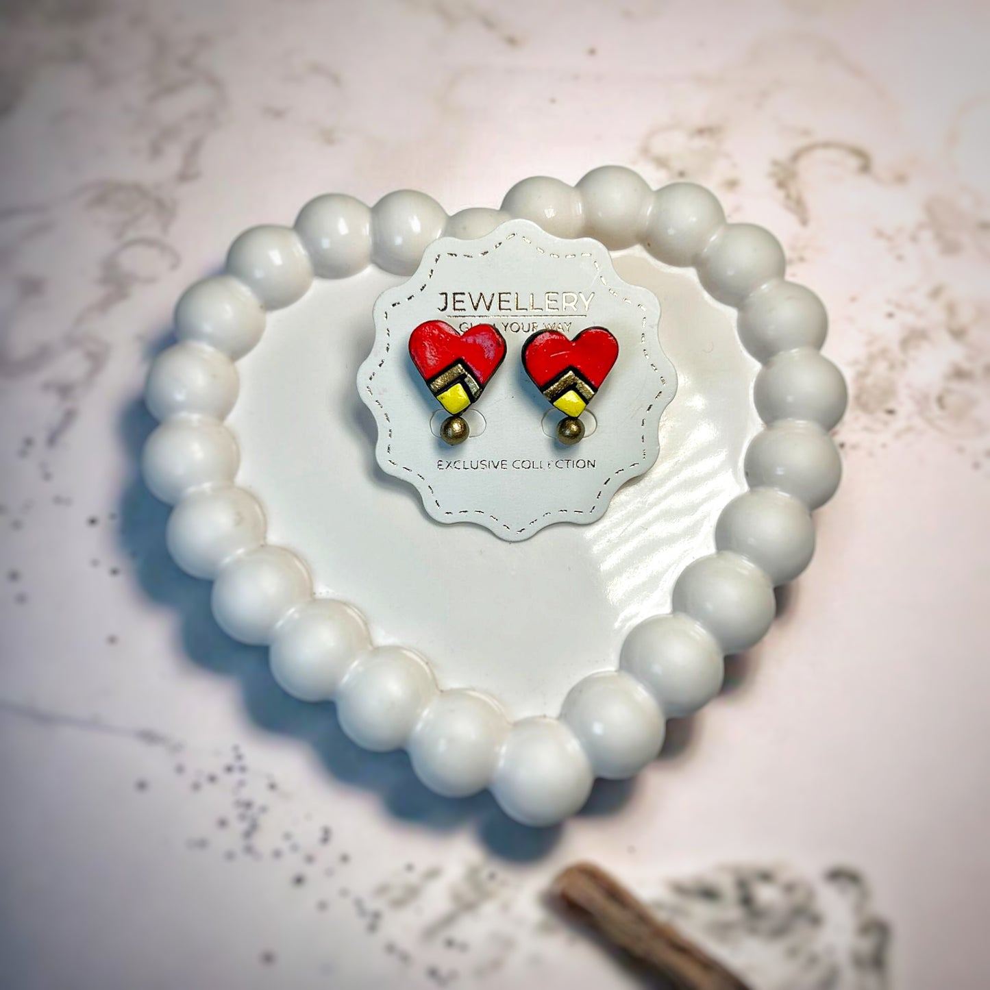Handmade Heart Studs Earrings Red with geometric design on white jewelry card inside heart-shaped white bead frame