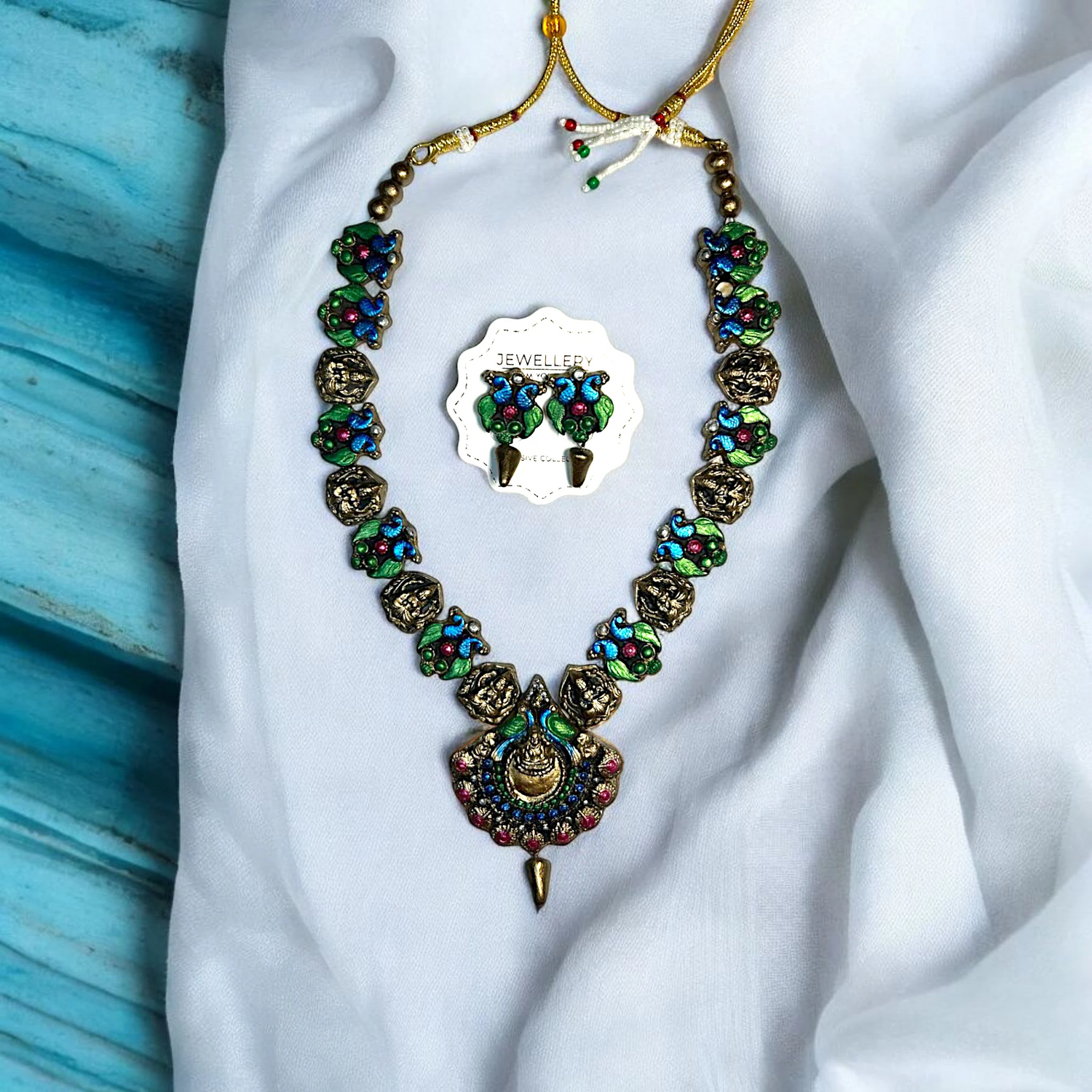 Colorful handmade necklace for women with matching earrings on white fabric background