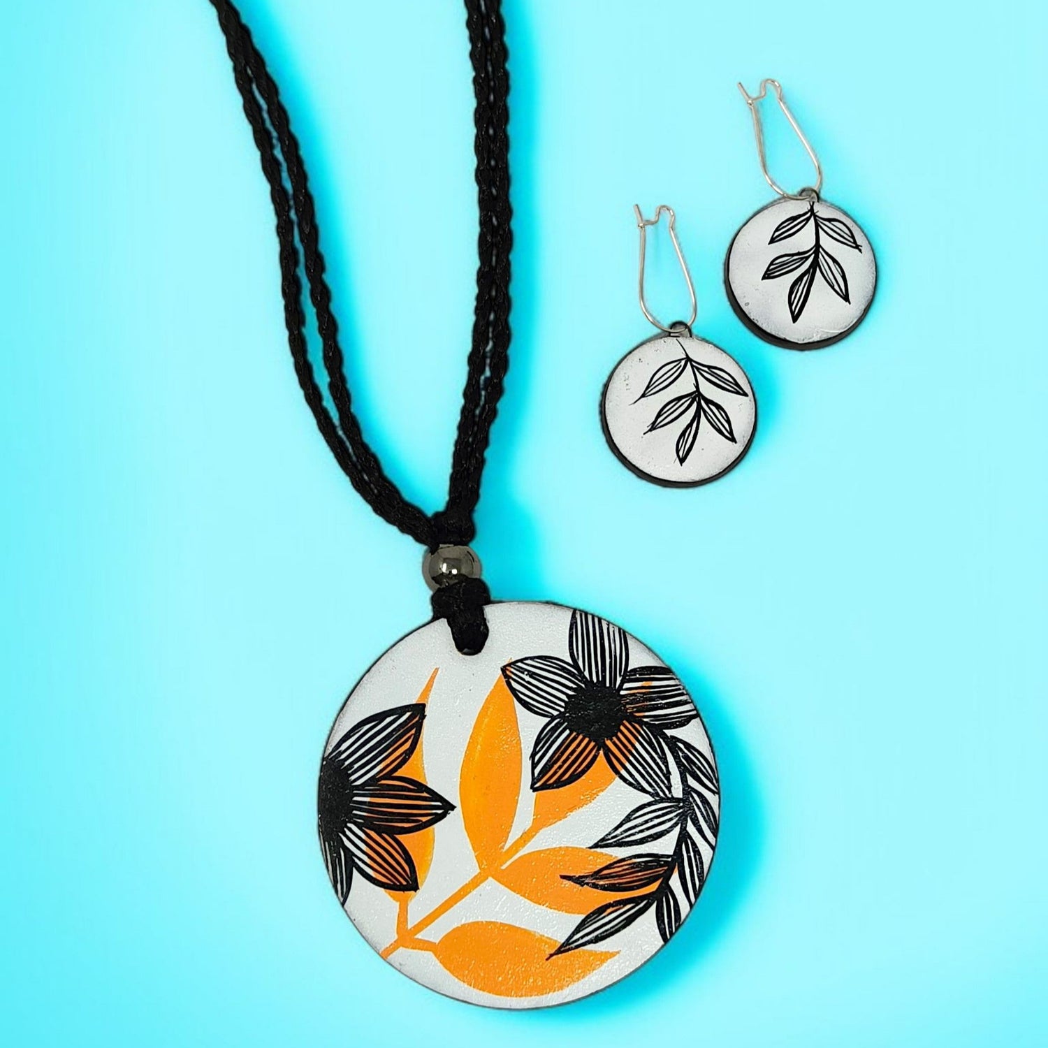 Artisan Floral Pendant Necklace with black and orange floral design on round pendant and matching earrings