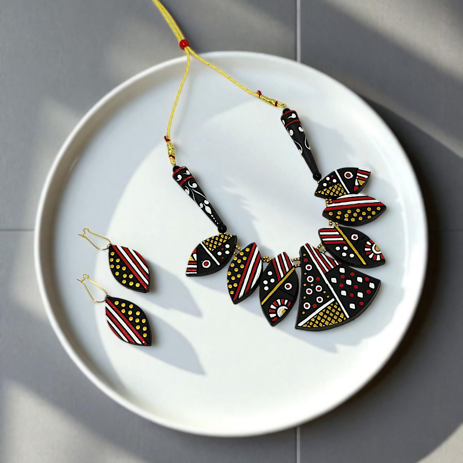 Black Trible jewelry Necklace Set with geometric patterns and matching earrings on white plate