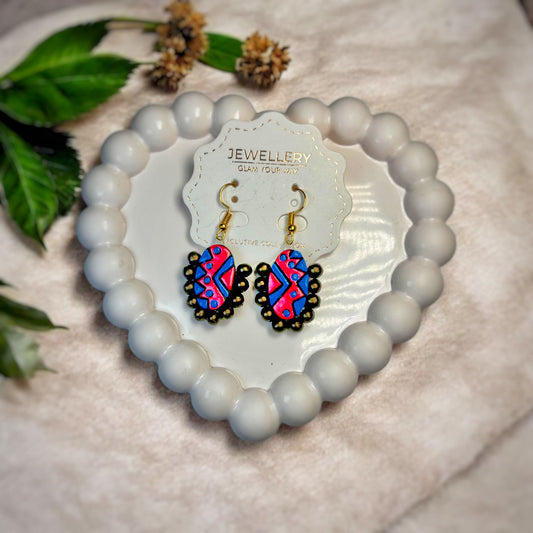 Buy Hand Painted Dangle Terracotta Stud Earrings in vibrant pink and blue with black detailing on a decorative white beaded holder