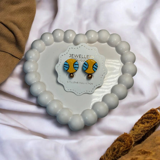 Handmade Ear Studs In Blue and Yellow displayed on white beaded heart-shaped tray by Mrritika