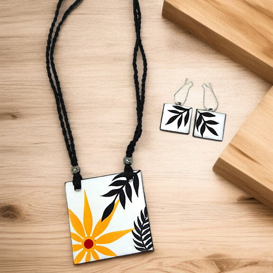 Handmade necklace for women with black cord and square pendant featuring yellow flower and black leaves design