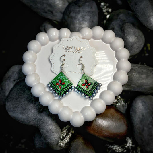 Handmade stud drop earrings with green square design and red floral pattern displayed on white bead heart stand