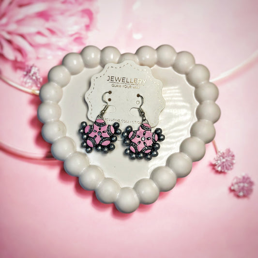 Traditional pink drop earrings with black bead accents displayed on a heart-shaped white tray