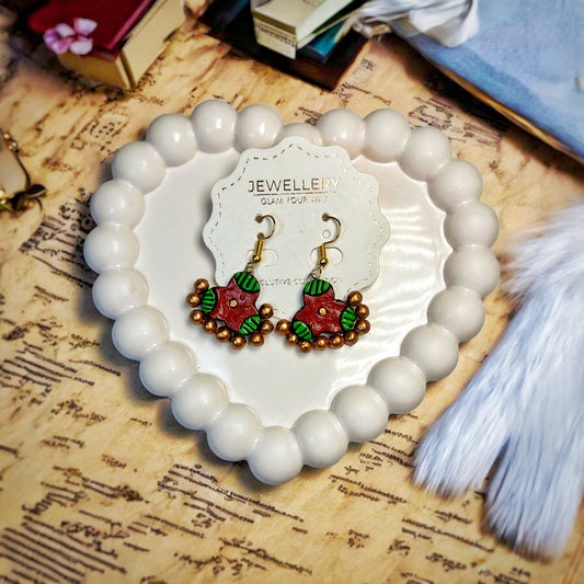Mrritika Handmade Clay Dream Earrings in red and green with golden bead accents displayed on a heart-shaped white bead tray