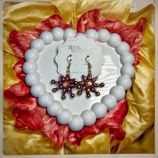 Traditional red handmade earrings with floral design displayed on white heart-shaped beads background